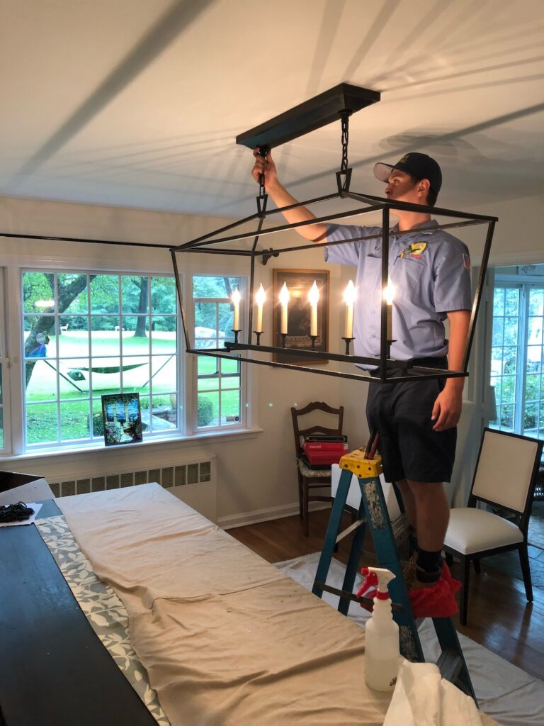 electrician hanging a light over a covered kitchen table