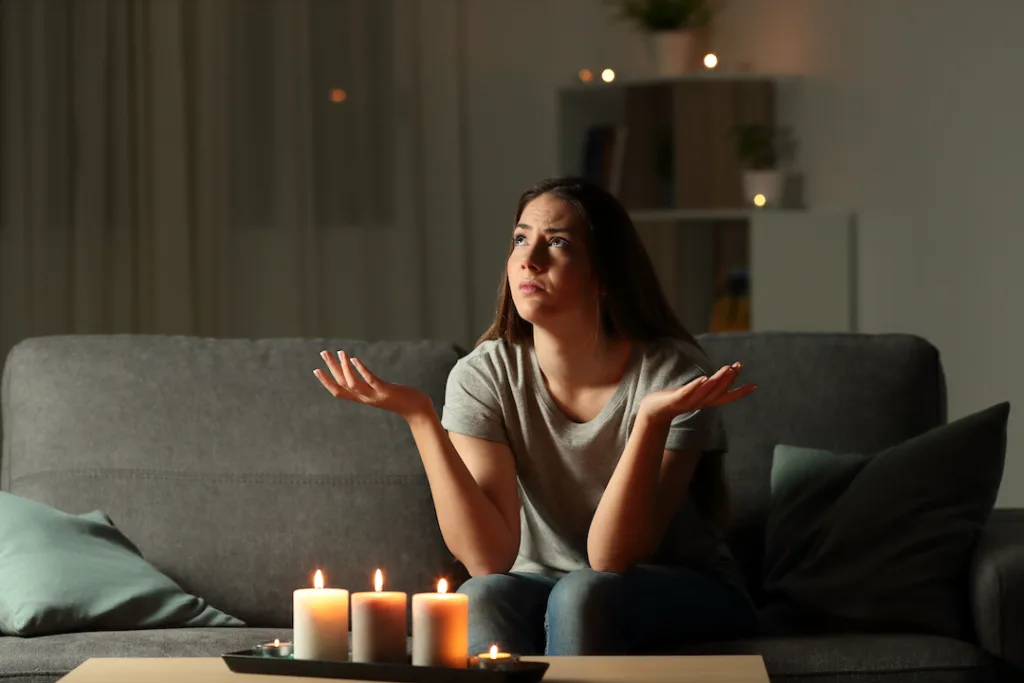 Woman complaining during a blackout sitting on a couch in the living room at home
