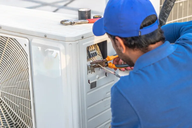 Electrician wiring a central air conditioning unit outdoors using insulated pliers, performing safe and professional AC electrical work.