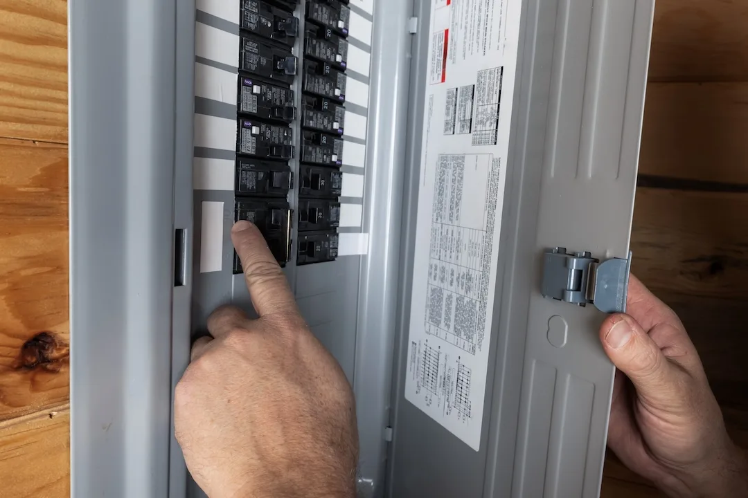 Close up of a home owner inspecting the electrical breakers or fuse box to restore power.